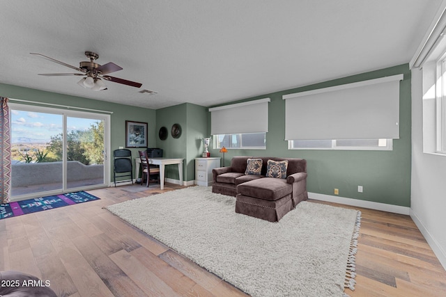 living room featuring visible vents, a textured ceiling, baseboards, and wood finished floors