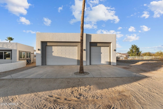 garage featuring concrete driveway and fence