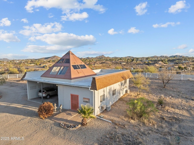 view of front of house with brick siding, a mountain view, a carport, and fence