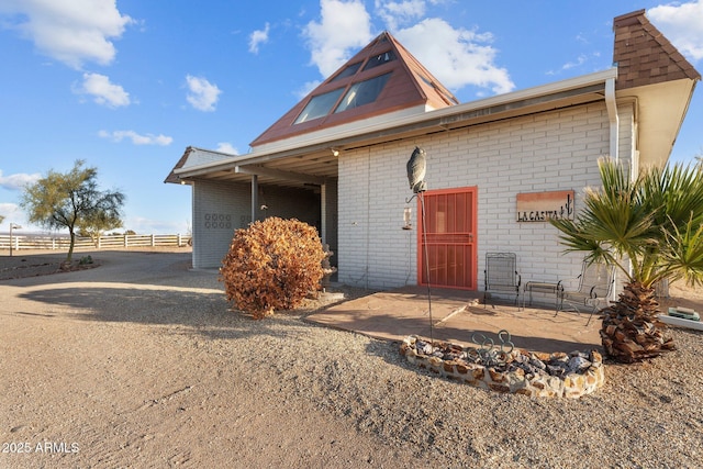 view of front facade featuring a patio, brick siding, and fence