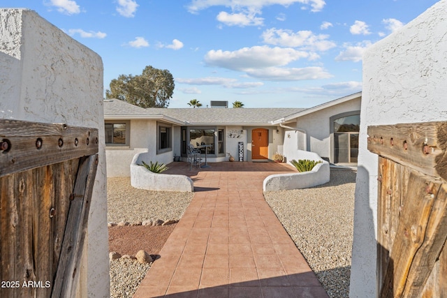 rear view of property with a patio, fence, roof with shingles, and stucco siding