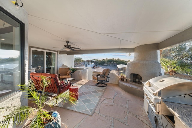 view of patio featuring a grill, exterior kitchen, a ceiling fan, and an outdoor living space with a fireplace