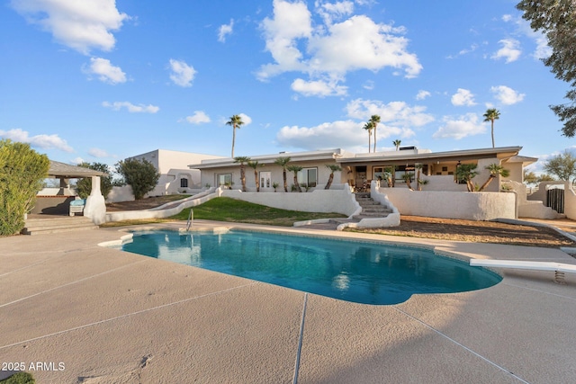 pool with a patio, fence, a water slide, a diving board, and stairs