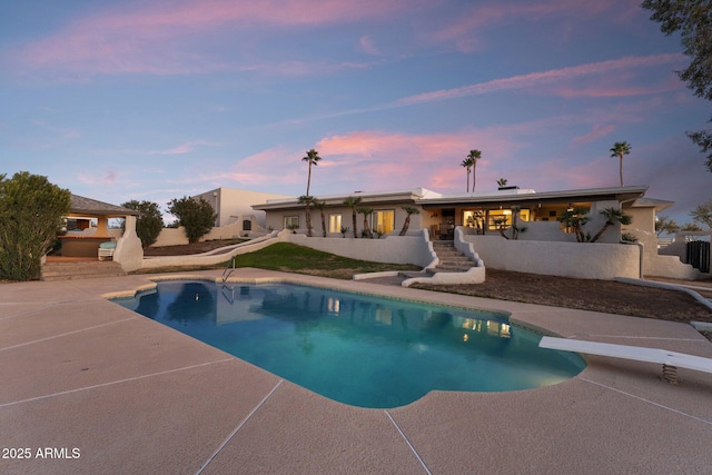 outdoor pool featuring fence, a patio, and a diving board