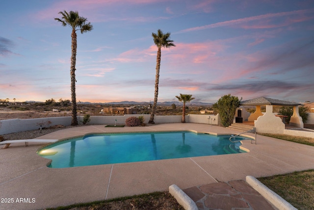 pool at dusk with a gazebo, a patio, a diving board, and an outdoor pool