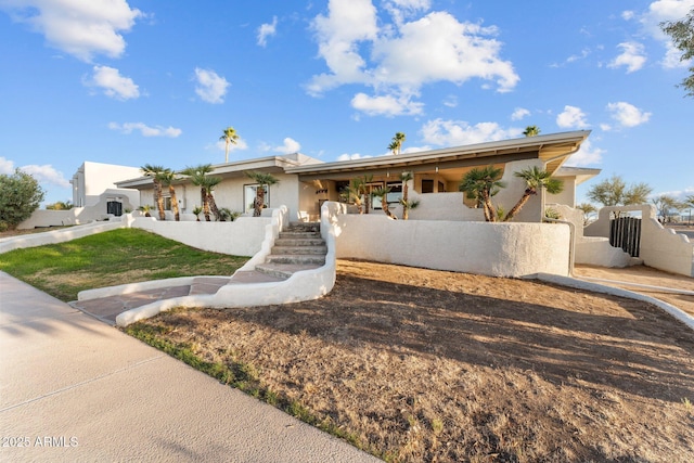 ranch-style house with stucco siding and fence