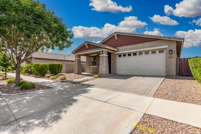 view of front facade featuring driveway, an attached garage, fence, and stucco siding