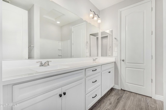 bathroom featuring double vanity, wood finished floors, and baseboards
