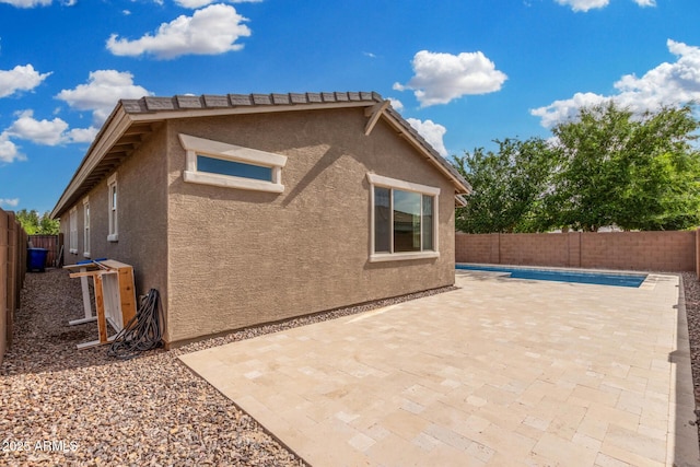 view of home's exterior with stucco siding, a fenced backyard, and a patio area