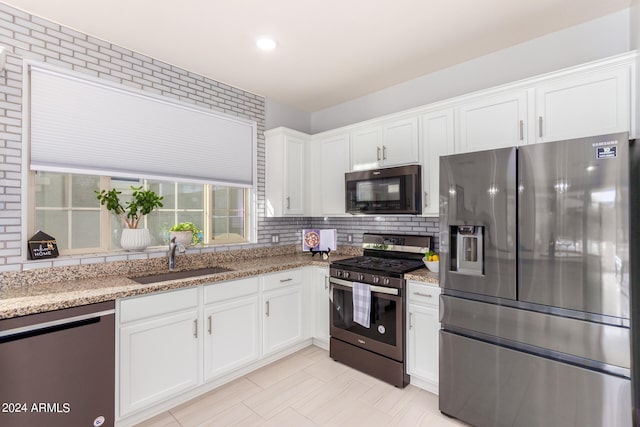 kitchen featuring light stone countertops, stainless steel appliances, sink, and white cabinetry