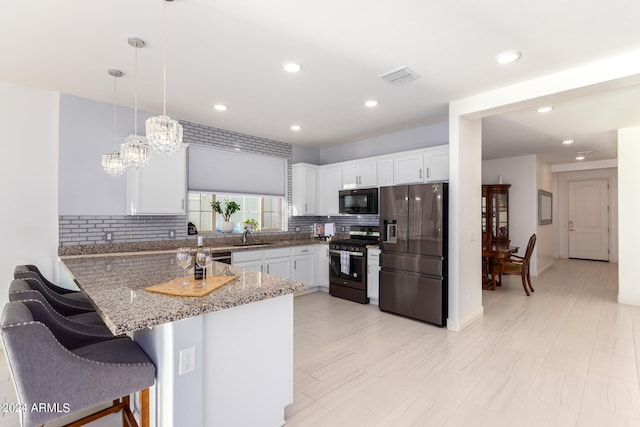 kitchen featuring stainless steel appliances, white cabinets, kitchen peninsula, and decorative light fixtures