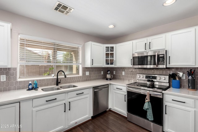 kitchen with visible vents, dark wood-type flooring, a sink, stainless steel appliances, and white cabinets