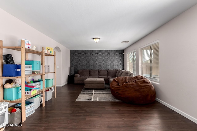 living room with an accent wall, baseboards, and wood finished floors
