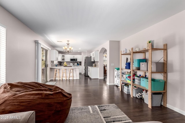 living room featuring an inviting chandelier, baseboards, dark wood-style flooring, and arched walkways