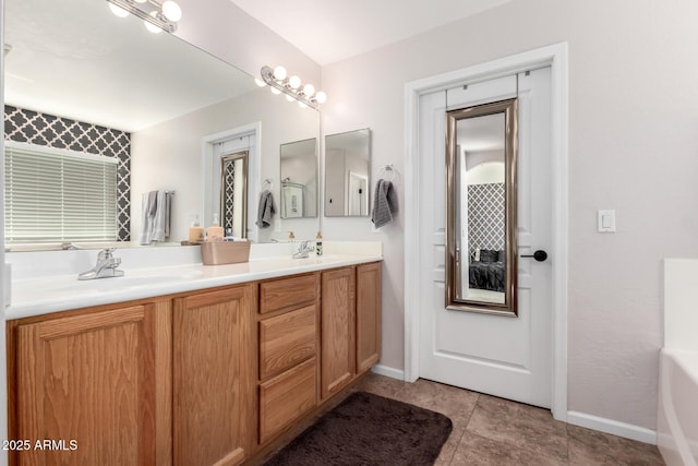 bathroom featuring double vanity, tile patterned flooring, baseboards, and a sink