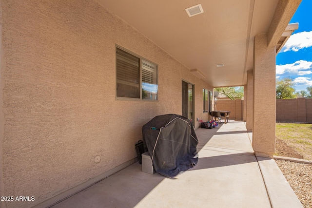 view of patio with visible vents, a grill, and fence