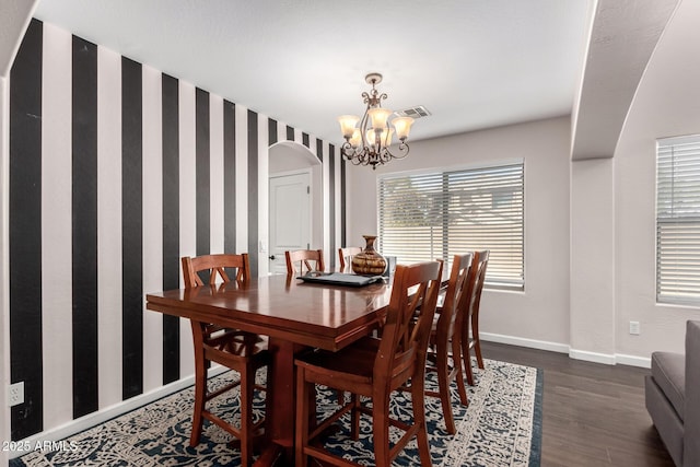 dining area with visible vents, a notable chandelier, dark wood-type flooring, arched walkways, and baseboards