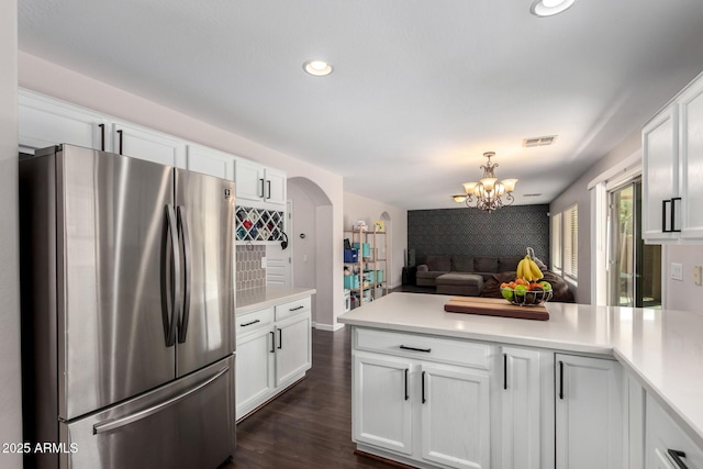 kitchen featuring visible vents, wallpapered walls, a peninsula, freestanding refrigerator, and an accent wall