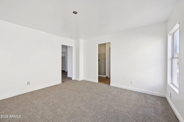 carpeted spare room featuring plenty of natural light and baseboards