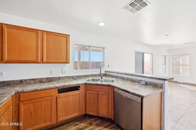 kitchen featuring a sink, visible vents, stainless steel dishwasher, brown cabinetry, and dark countertops