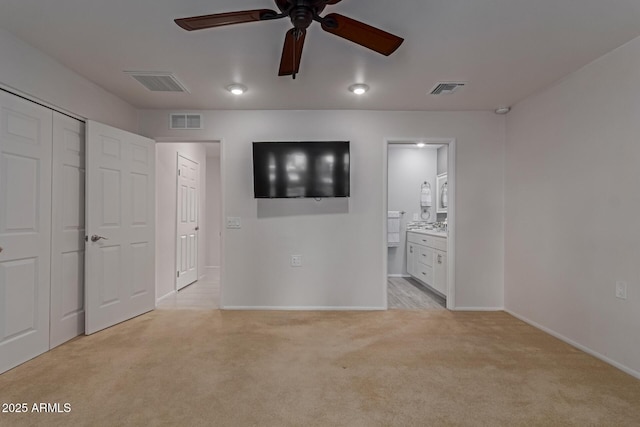 unfurnished bedroom featuring visible vents, ensuite bathroom, and light carpet