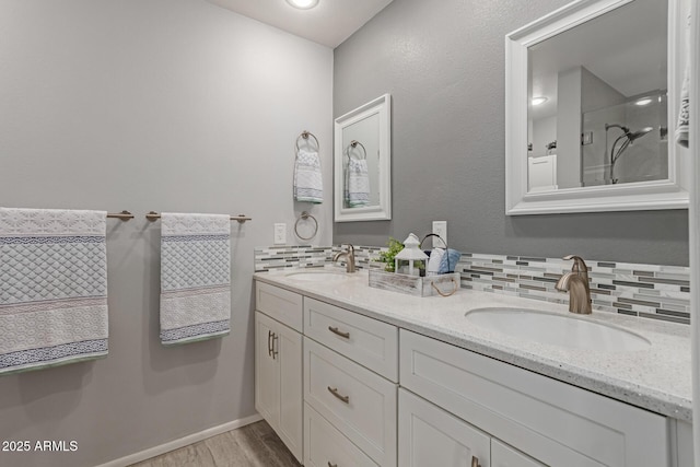 full bathroom with decorative backsplash, double vanity, wood finished floors, and a sink