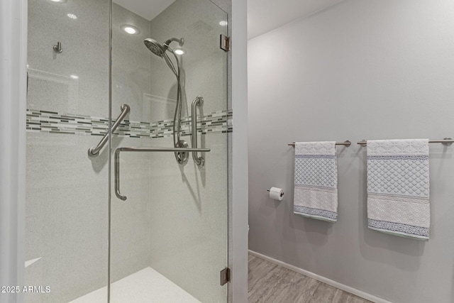 full bath featuring a stall shower, baseboards, and wood finished floors