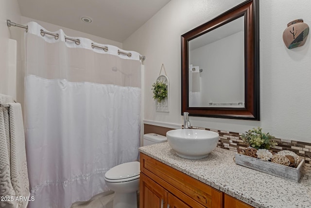 bathroom featuring decorative backsplash, curtained shower, toilet, and vanity