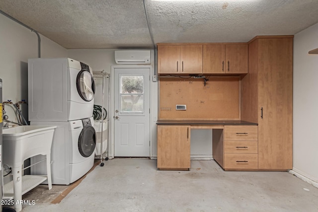 laundry room featuring an AC wall unit, stacked washer / dryer, and a textured ceiling