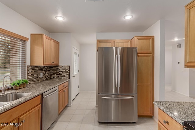 kitchen with tasteful backsplash, light stone counters, light tile patterned flooring, stainless steel appliances, and a sink