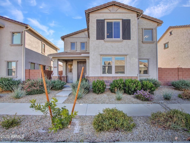 view of front of home featuring stone siding, a tiled roof, fence, and stucco siding