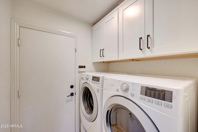 clothes washing area with washing machine and dryer and cabinet space