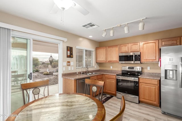 kitchen featuring ceiling fan, appliances with stainless steel finishes, light hardwood / wood-style floors, and sink