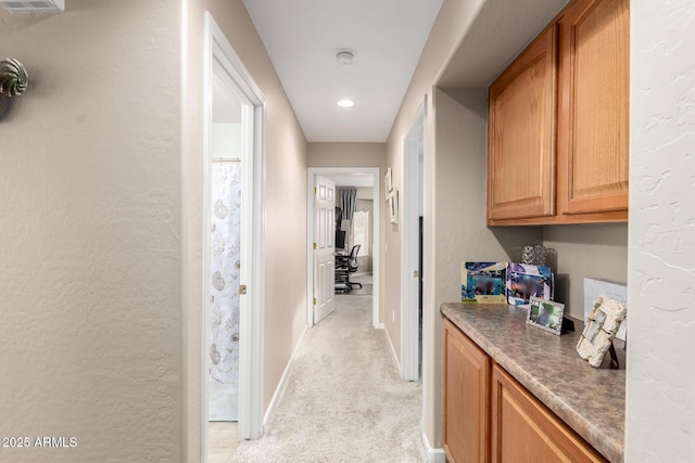 hallway featuring light colored carpet