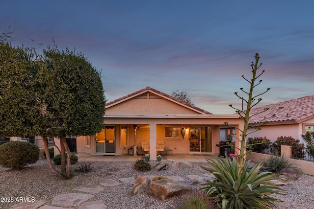 back house at dusk featuring a patio area