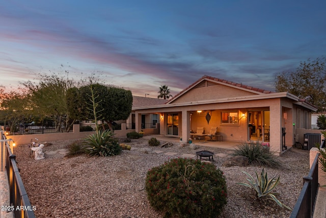 back house at dusk with central AC unit and a patio area