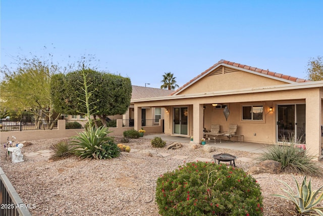 rear view of property featuring a fire pit and a patio area