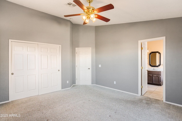 unfurnished bedroom with sink, ensuite bath, light carpet, a closet, and ceiling fan