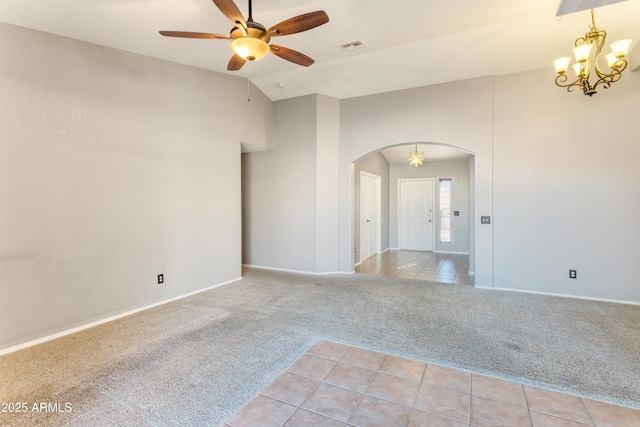 carpeted spare room featuring ceiling fan with notable chandelier and vaulted ceiling