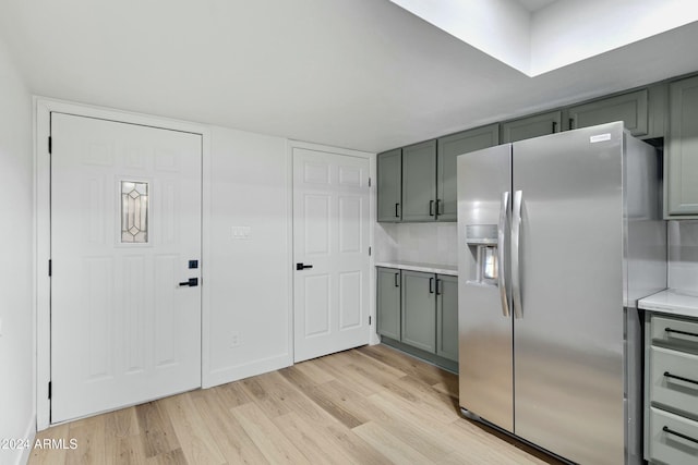 kitchen with stainless steel fridge, tasteful backsplash, and light hardwood / wood-style flooring