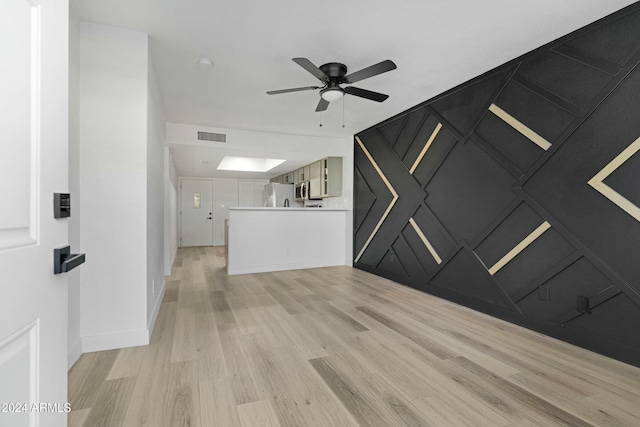 unfurnished living room with a skylight, light hardwood / wood-style flooring, and ceiling fan