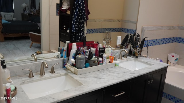 bathroom featuring a bathing tub, double vanity, and a sink