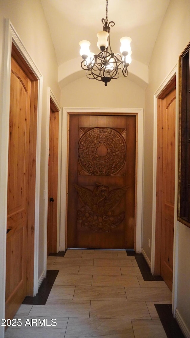 doorway to outside with wood tiled floor, baseboards, vaulted ceiling, and a chandelier