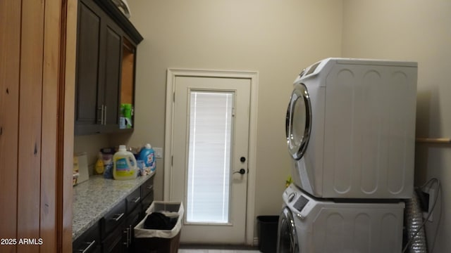 washroom featuring stacked washer and dryer and cabinet space