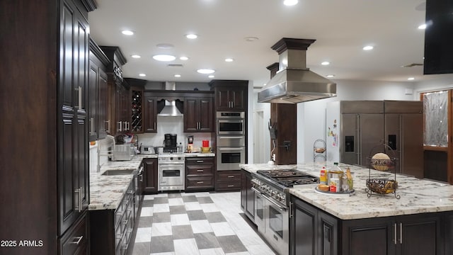 kitchen featuring wall chimney exhaust hood, stainless steel appliances, a sink, island range hood, and a spacious island