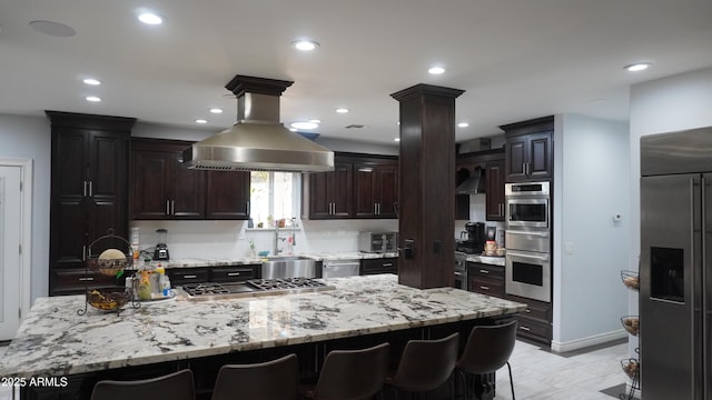 kitchen with island exhaust hood, a sink, a breakfast bar area, and appliances with stainless steel finishes