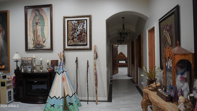 hallway featuring arched walkways and an inviting chandelier