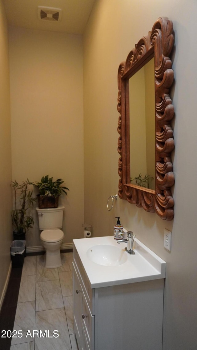 bathroom featuring baseboards, visible vents, toilet, and vanity
