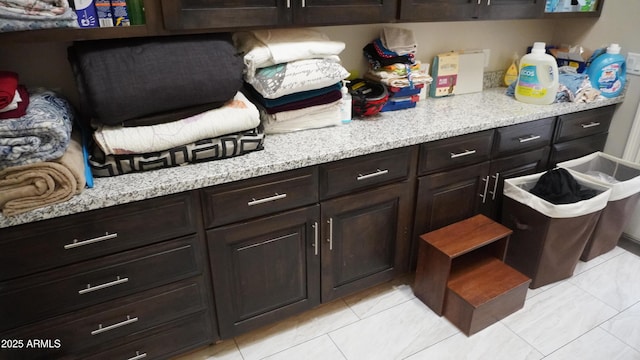 kitchen featuring light stone countertops, dark brown cabinetry, and open shelves