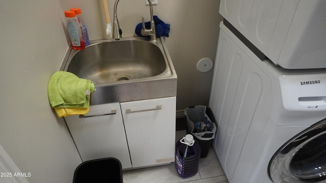 clothes washing area with light tile patterned floors, a sink, cabinet space, and stacked washing maching and dryer